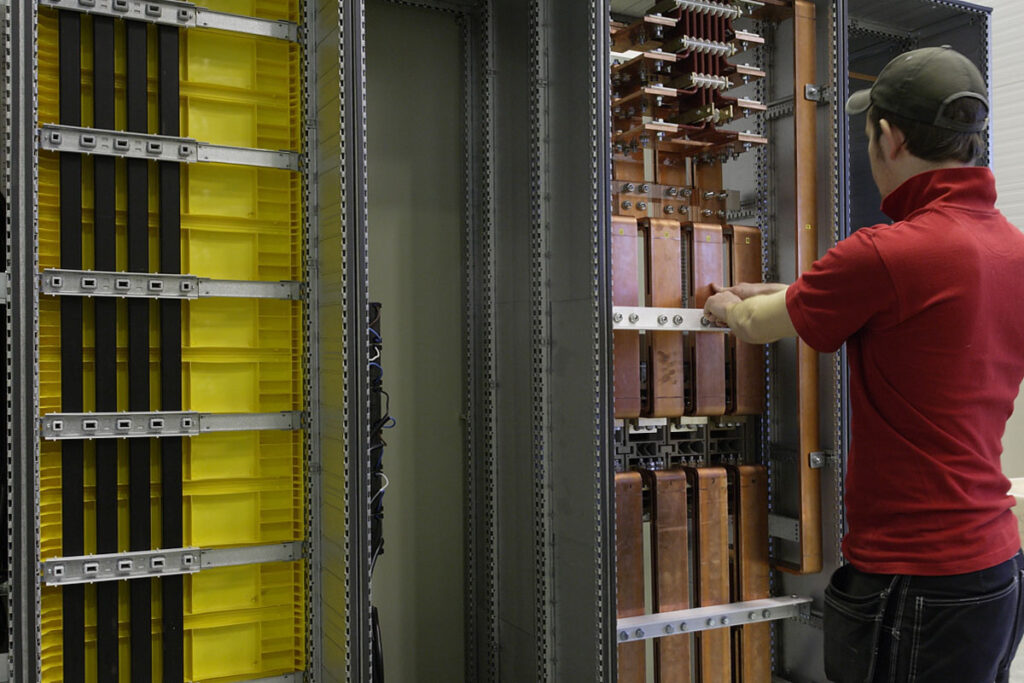 A person assembles an electrical cabinet