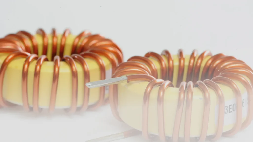 Two toroidal inductors with yellow cores and copper windings on a light background